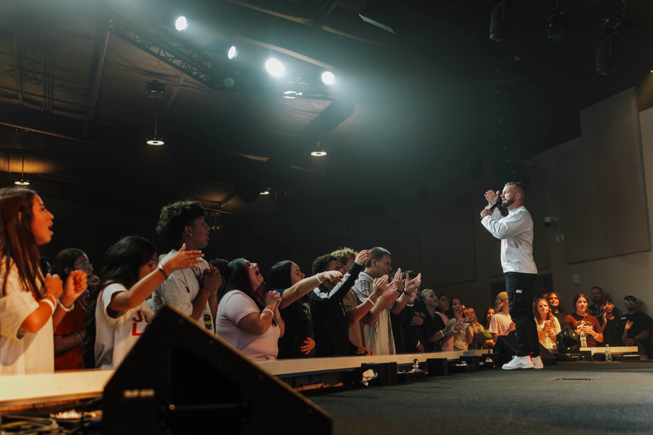 Tyler preaching to a crowd with hands raised